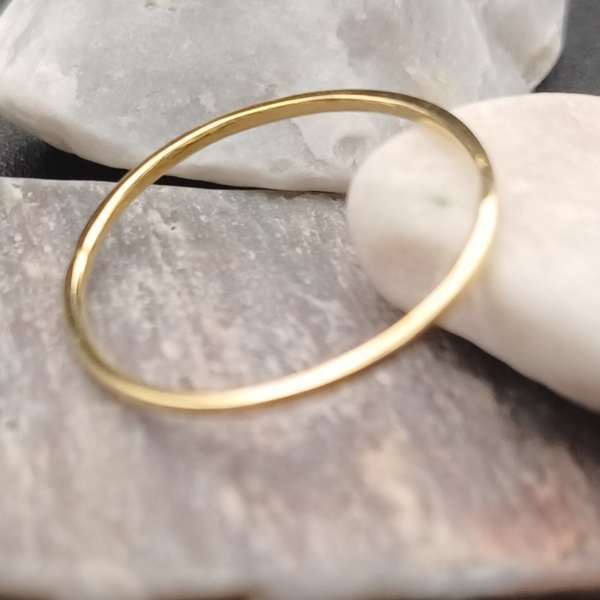 Notre anneau, modèle simple, en plaqué or. Disposé sur des pierres.