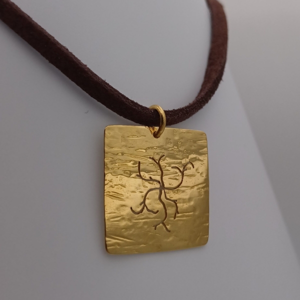 Notre pendentif, modèle branches sauvages carré, en plaqué or, avec un cordon marron.