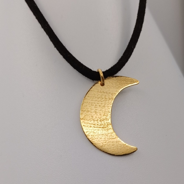 Notre pendentif, modèle demi lune grand, en plaqué or. Sur cordon noir.