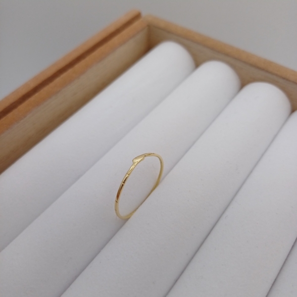 Notre anneau pour femme, modèle brindille en plaqué or, disposé sur un présentoir à bijoux.