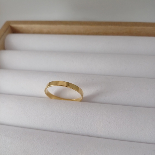 Notre anneau, modèle simple large, en plaqué or, disposé sur un présentoir à bijoux.