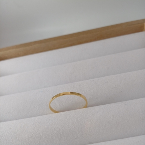 Notre anneau, modèle simple medium, en plaqué or, disposé sur un présentoir à bijoux.